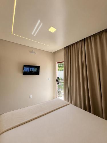 a bedroom with a bed and a tv on the wall at Casa Dona Amélia in Barreirinhas