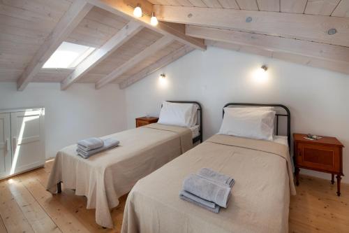 two beds in a room with white walls and wooden floors at Amaranthus house in Longós