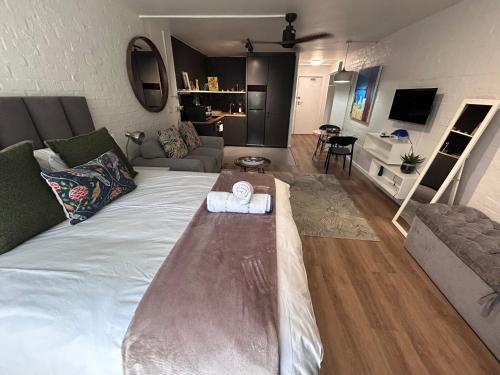 a living room with a large bed with a table at Greenpoint Chic Studio Apartment in Cape Town