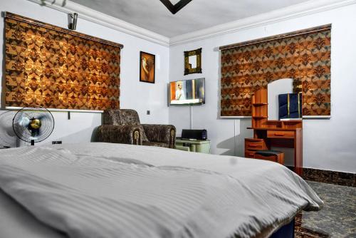 a bedroom with a bed and a chair and a television at Lodgeselect in Ibadan