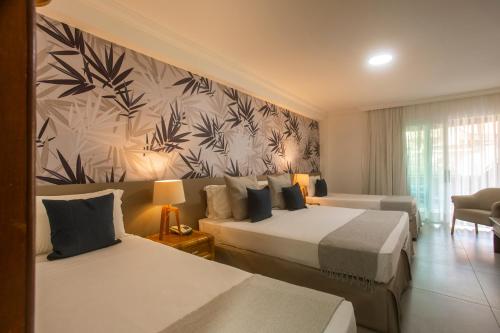 a hotel room with two beds and a wall at Armação Resort Porto de Galinhas in Porto De Galinhas