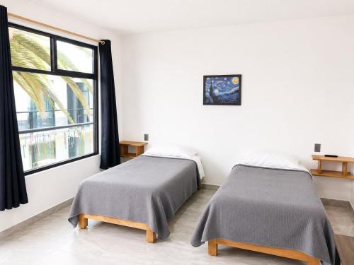 two beds in a room with a window at La Palma Coliving in San Lucas Xoloc