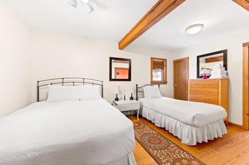 two beds in a bedroom with white walls and wood floors at River Road Treehouse Retreat in Warrensburg