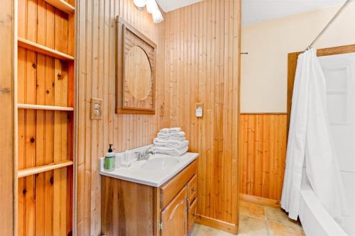 a bathroom with a white sink and wooden walls at River Road Treehouse Retreat in Warrensburg