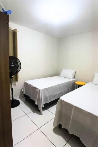 a room with two beds and a fan at Apto Completo São João com Garagem e Piscina in Campina Grande