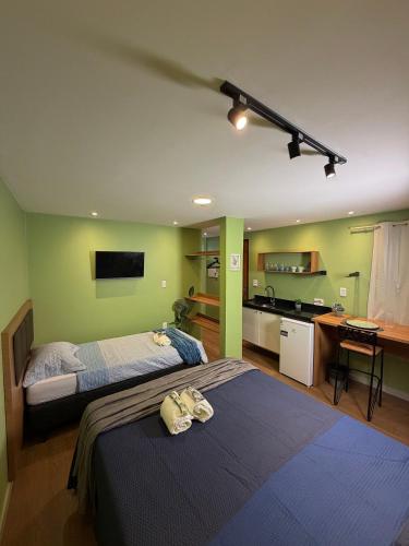 a bedroom with two beds and a kitchen with a sink at Studios Caripunas Reformado Localização Central in Belém