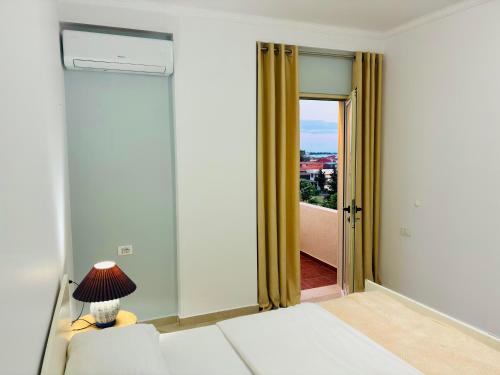 a room with a bed and a door with a window at Arc Apartment Family - City Center in Divjakë