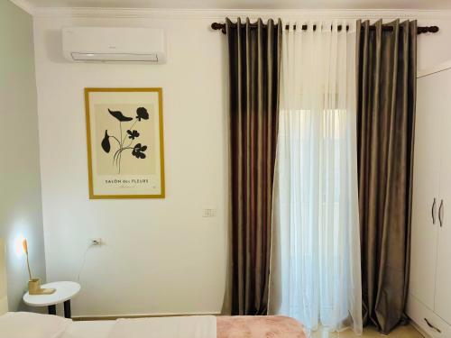 a bedroom with a bed and a window with curtains at Arc Apartment Family - City Center in Divjakë