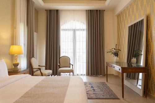 a hotel room with a bed and a desk and a window at Alyasa Village in Jbeil