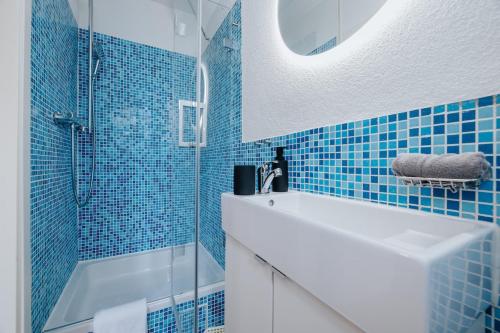 a blue tiled bathroom with a sink and a shower at Frisch sanierte Wohnung mit zwei Schlafzimmern in historischem Baudenkmal in Feldberg