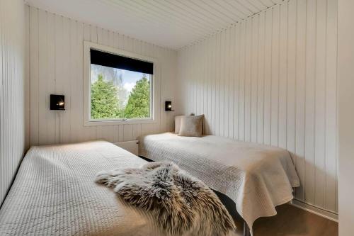 a white bedroom with two beds and a window at C11347-Tarm-Baeverstien-8 in Tarm