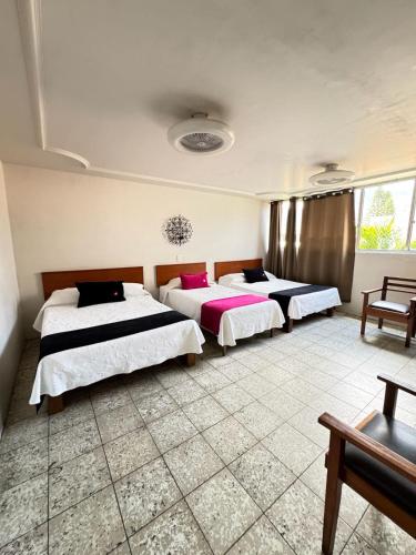 three beds in a room with a tiled floor at HOTEL FLAMINGOS DE CIUDAD GUZMAN in Ciudad Guzmán