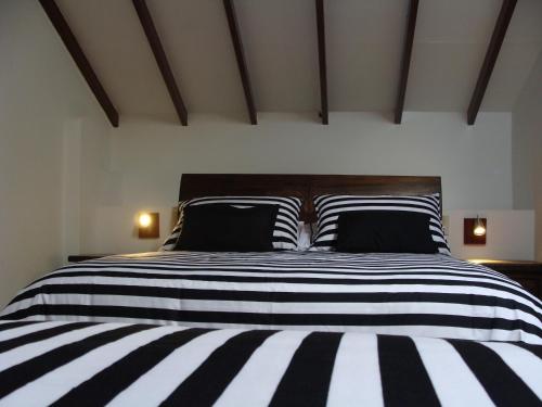 a bedroom with a black and white bed with two pillows at Villa Pepita Real in Villa de Leyva