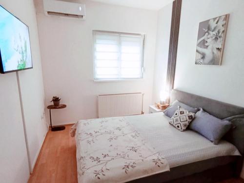 a small bedroom with a bed and a television at Apartman 053 in Doboj