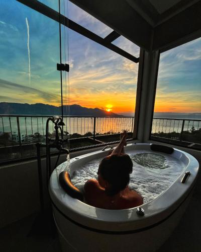 a person in a bath tub with a view of the ocean at Casa Gaia GuestHouse in Ilhabela