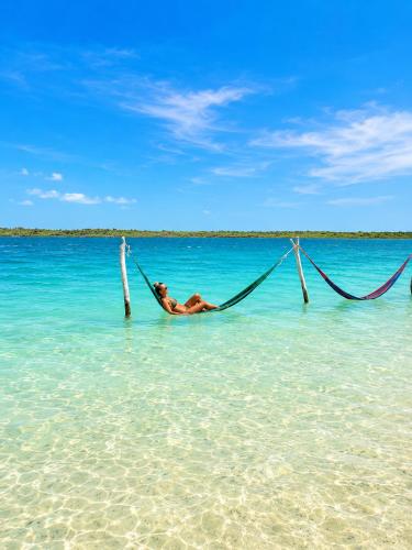 a man laying in a hammock in the ocean at Maruá Pousada da Lagoa in Jijoca de Jericoacoara