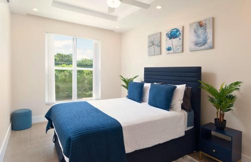 a bedroom with a blue and white bed and a window at Modern 2BR Beachside Haven Ground Floor and Pool in Saint Peter