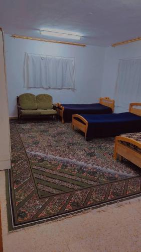 a living room with two beds and a rug at Lovely hotel in Al Qābūţī