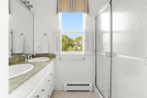 a white bathroom with two sinks and a shower at Waterfront Estate w Hot Tub, Dock & Kayaks in Stonington