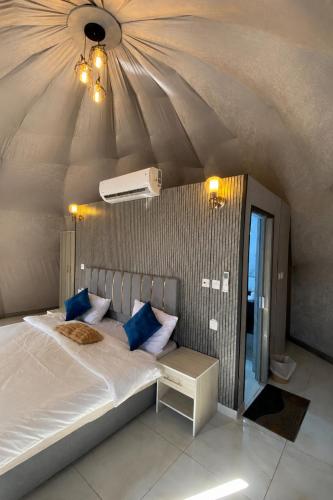 a bedroom with a large bed with blue pillows at Olivia Rum Luxury Bubbles & Jeep Tours in Wadi Rum