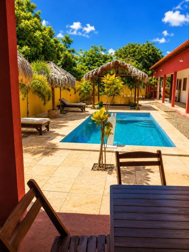 a swimming pool with a chair and a bench next to a house at Maruá Pousada da Lagoa in Jijoca de Jericoacoara