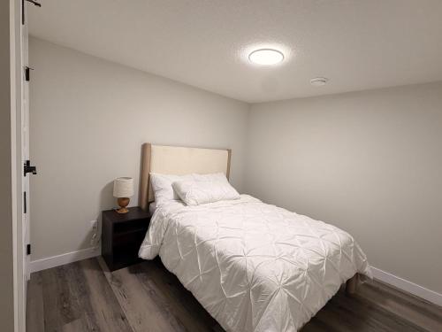 a white bedroom with a bed and a night stand at Eden Secret YYC in Calgary