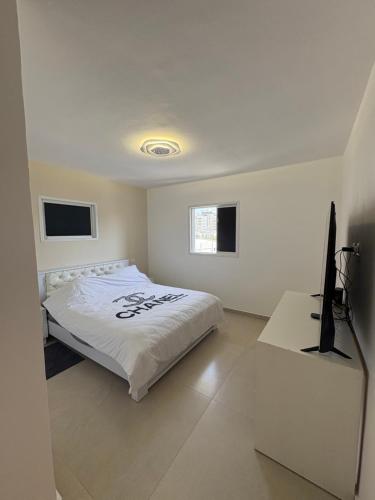 a bedroom with a bed and a flat screen tv at Mykonos unite in Rishon LeẔiyyon