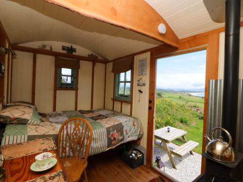 ein Schlafzimmer mit einem Bett, einem Tisch und einem Fenster in der Unterkunft Cwt Bugail in Pwllheli
