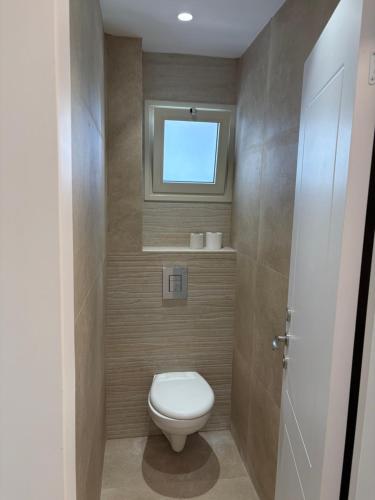a small bathroom with a toilet and a window at Mykonos unite in Rishon LeẔiyyon