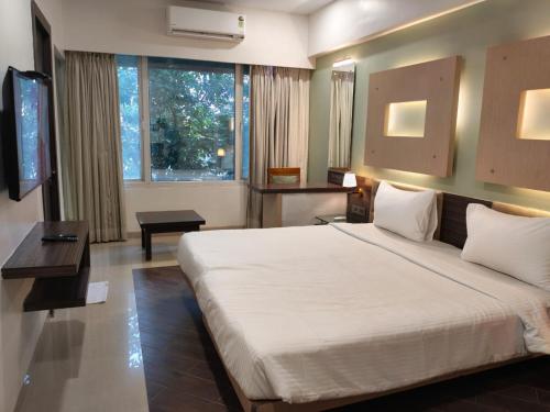 a bedroom with a large white bed and a television at Hotel Mumbai House Thane in Thane