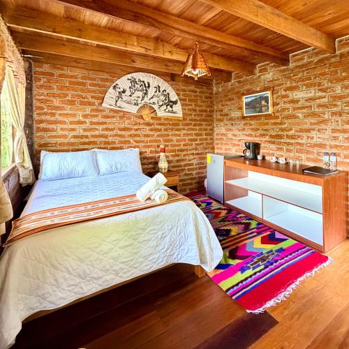 a bedroom with a bed and a brick wall at Hospedaje Puntzán in Baños