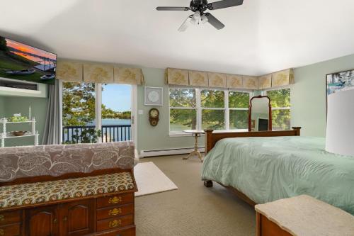 a bedroom with a bed and a couch and windows at Waterfront Estate w Hot Tub, Dock & Kayaks in Stonington