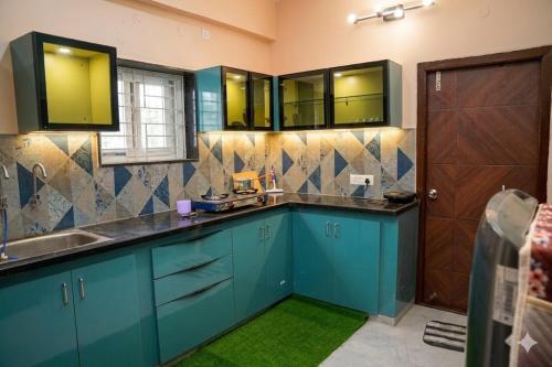 a kitchen with blue cabinets and a sink and a door at The jaish heaven in Rushikonda