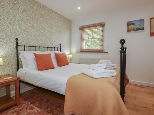 a bedroom with a bed with white sheets and orange pillows at 15 Boscaswell Downs in Penzance