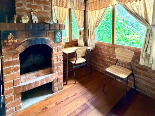 a living room with a brick fireplace and two chairs at Hospedaje Puntzán in Baños