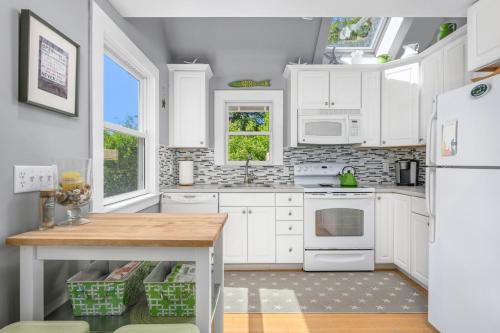 a kitchen with white cabinets and a wooden table at Cape Cod Cottage near Beaches & Downtown in Chatham