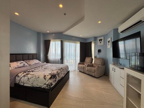 a bedroom with a bed and a couch and a television at Ocean View Corner Studio Private Balcony Tambuli Tower F in Maribago