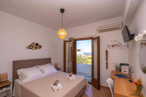 a bedroom with a bed and a desk and a window at Flo Guest House in Sifnos