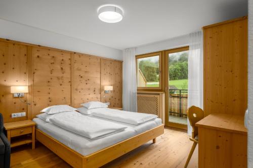 a bedroom with a bed and a desk and a window at Ferienwohnung Mair am Bach in Brunico