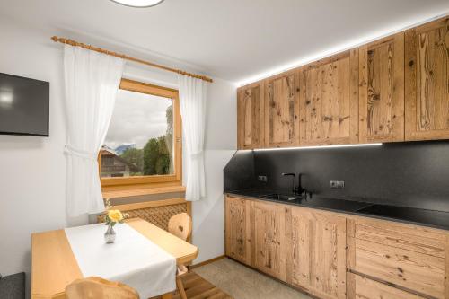 a kitchen with wooden cabinets and a table and a window at Ferienwohnung Mair am Bach in Brunico