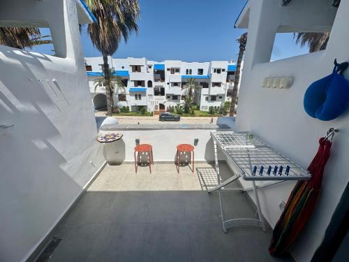 a balcony with two chairs and a table and a pool at Magnifique appartement Bahia Smir Fnideq Mdiq nord in Fnidek