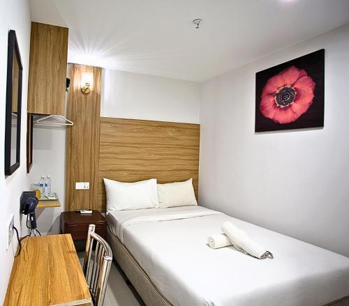 a bedroom with a bed and a table and a red flower on the wall at Hotel EcoStay at Chow kit in Kuala Lumpur