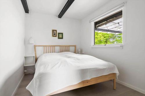 a white bedroom with a bed and a window at 40583-Juelsminde-Pot-Strandby-119 in Sønderby