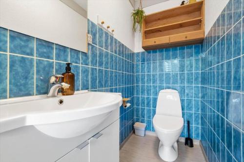 a blue tiled bathroom with a sink and a toilet at 40583-Juelsminde-Pot-Strandby-119 in Sønderby