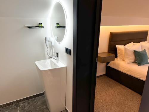 a bathroom with a sink and a mirror next to a bed at Royal Wood Hotel in Rokytne