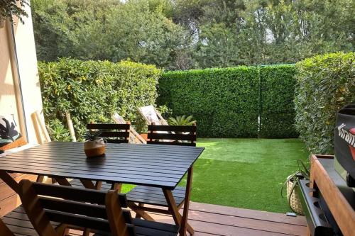 a wooden table and chairs on a deck with a yard at Cozy studio with pool near the seaside in Roquebrune-sur-Argens