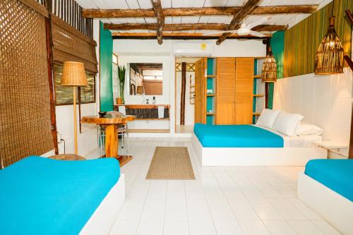 a room with two blue beds and a kitchen at Hotel PlayaScondida Baru in Barú