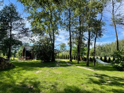 a garden with a hammock and a barn at RiverHouse in Bałtów
