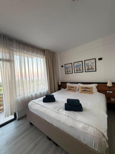 a bedroom with a large bed with two blue pillows on it at Hotel Amur in Corbu