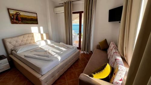 a bedroom with a bed and a couch and a window at Erjani Hotel in Velipojë
